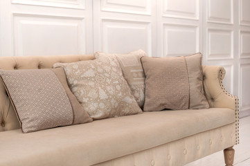 Luxury design elements: beige cushions with Christmas pattern on beige old style couch in white room