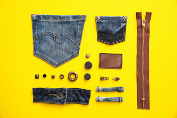 Flat lay composition with garment accessories and cutting details for jeans on yellow background