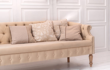 Luxury design elements: beige cushions with Christmas pattern on beige old style couch in white room