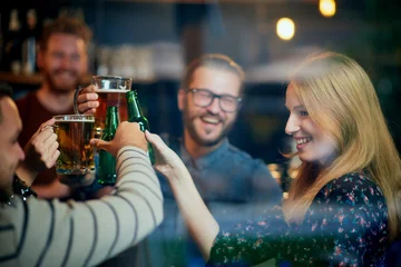 Group of best friends standing at pub and toasting with beer. Nightlife.