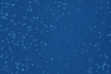 Fototapeta premium Monochrome metallic foil confetti background. Trendy classic blue colored circles and stars sparse on dark blue green colored paper. Simple holiday concept. Top view, flat lay. Color of the year 2020