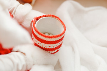 Children's hands in white fur mittens hold a mug with red and white knitted decor