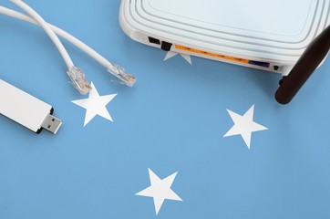 Micronesia flag depicted on table with internet rj45 cable, wireless usb wifi adapter and router....