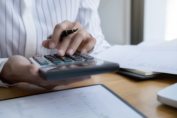 Close-up of businessman hand using calculator to calculate business data, accountancy document at home office.