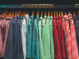picture of colourfull  clothes on wooden hangers in a shop under a bright yellow spotlight. Moodie picture for artistic purposes 