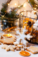 Metal basket with delicious homemade gingerbread cookies decorated with icing. Rustic decor, christmas lights on. Festive mood, holiday atmosphere. Front view, closeup, white background