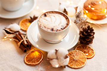 Cozy and romantic holiday time. Winter hot drink in white cup. Christmas lights on, festive mood, atmosphere of relax, family time. Top view, white background, close up