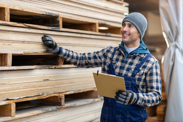 Naklejka na ściany i meble Young male worker in timber warehouse 