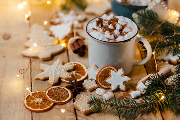 Obraz na płótnie Canvas Winter hot drink: white mug with hot chocolate with marshmallow and cinnamon. Cozy home atmosphere, festive holiday mood. Rustic style, wooden background. Homemade gingerbread cookies