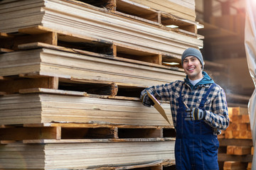 Naklejka na ściany i meble Young male worker in timber warehouse 