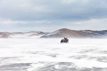 Tourists family travel by ATV on Lake Baikal in a snowy day along the island of Olkhon. Winter active holidays