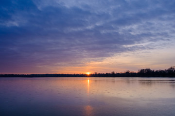 Fototapeta na wymiar Ice on the frozen Lake and cirrus clouds in the sky before sunrise. Beautiful ukrainian landscape