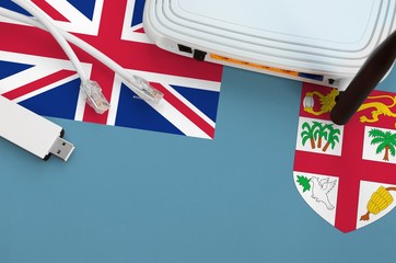 Fiji flag depicted on table with internet rj45 cable, wireless usb wifi adapter and router....