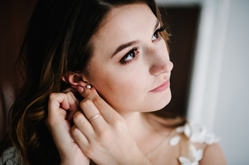 In the hands of the bride decoration in the form of a earring. Wedding Morning. Jewelry. Close-up...