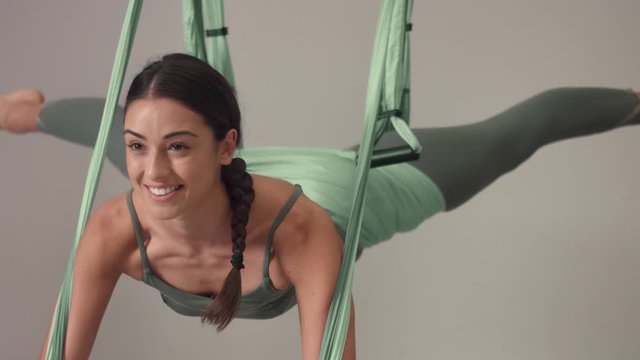 tilted movement of arial yoga element with female smiling yoga teacher, flying aerial yoga pose
