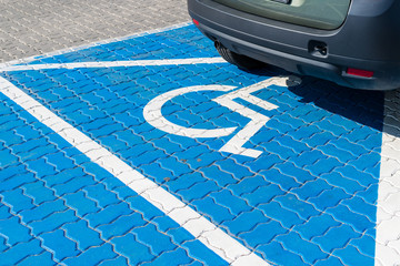 Parking spot for people with functional impairment. Vehicle on a fresh blue painted parking place....