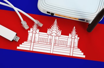 Cambodia flag depicted on table with internet rj45 cable, wireless usb wifi adapter and router....