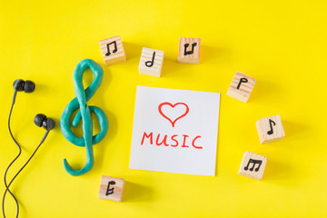 Treble clef and notes drawn on wooden cubes on the yellow background, music concept.