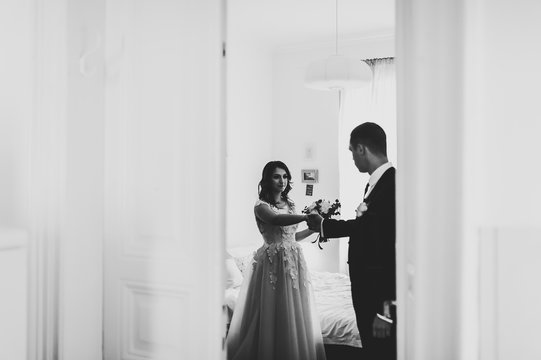 Artwork, noise, grain. The first meeting of the newlyweds at home, view through the door. The bridegroom takes the bride by hand. Black and white photo. Wedding Morning.