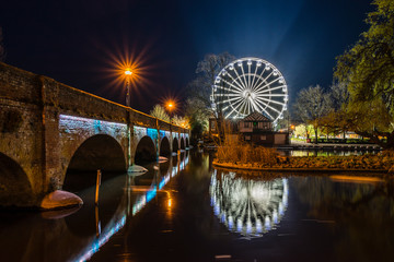 The ferris wheel at Waterside, Stratford upon Avon,  illuminated against the night sky and reflected in the River Avon.