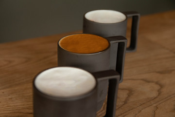 Three glasses of white and brown foam coffee latte on a wooden table