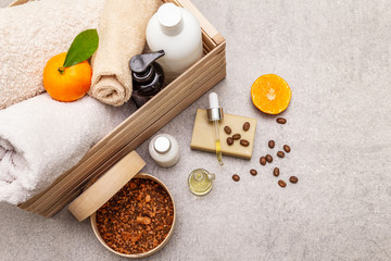 Coffee and tangerine spa concept. Towels, oil, scrub, soap, lotion. Natural ingredient, wooden box. Stone concrete background