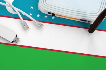 Uzbekistan flag depicted on table with internet rj45 cable, wireless usb wifi adapter and router....