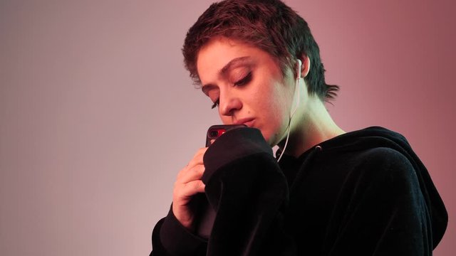 a short-haired girl is waiting for a message. She put the phone to her lips and looks directly at the camera. 4k