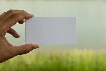 woman hand holding white paper with green nature background