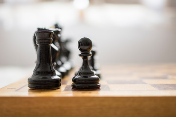 Chess chips, in the foreground a pawn and a black tower, on the board, ready to start the game.