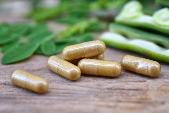 Close up  Herbal capsules from moringa herbs on rustic wooden table,background and copy space for using in medical background, healthy eating for good life. Selective focus