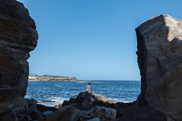 Man between two big rocks facing to the sea