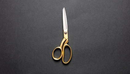 Pair of scissors gold handle isolated on black background, top view - obrazy, fototapety, plakaty