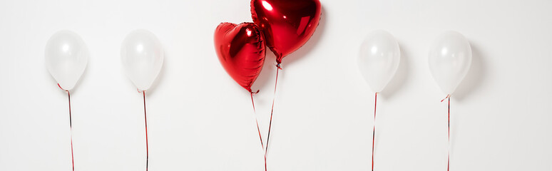 panoramic shot of red heart shaped balloons on white