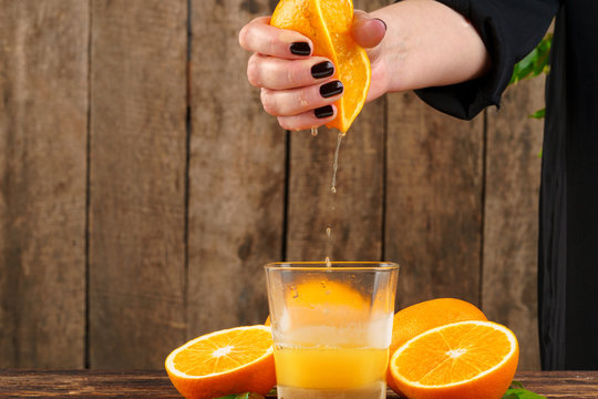 Woman hand squeezes orange juice close up
