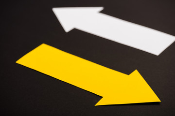 selective focus of yellow directional arrow isolated on black