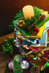 a stack of books with Christmas decorations and a burning candle.