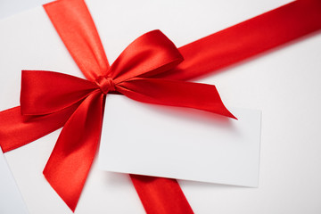 blank card near red ribbon with satin bow on white