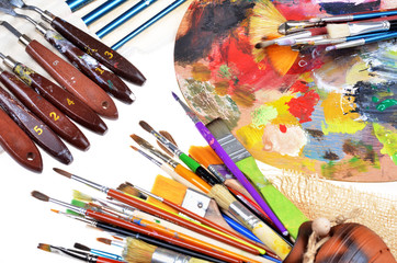 Fototapeta premium close-up view of artist workplace with paints brushes and palette on an isolated white background,selective focus