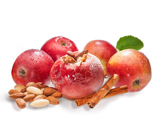 Bratäpfel und frische Äpfel mit Nüssen, Puderzucker und Zimtstangen auf weißem Grund