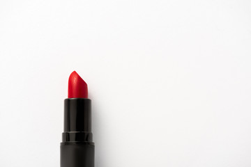 top view of black tube with red lipstick on white with copy space