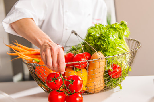 Korb mit frischem Gem&uuml;se in der K&uuml;che, Tomaten werden von der K&ouml;chin ausgepackt