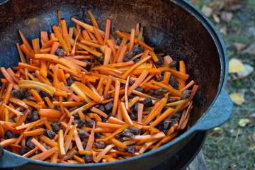 Fry sliced carrots in pilaf oil. Onions and carrots are fried in a pan in sunflower oil