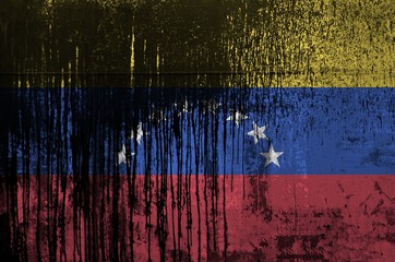 Venezuela flag depicted in paint colors on old and dirty oil barrel wall closeup. Textured banner on rough background
