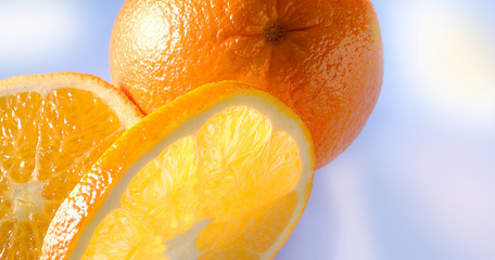 Saftige Orangenscheiben und  ganze Orange auf blauem Untergrund