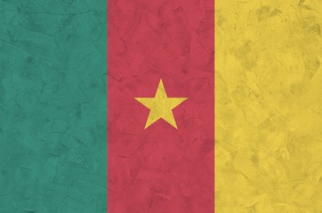 Cameroon flag depicted in bright paint colors on old relief plastering wall. Textured banner on...