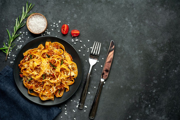 Pasta Bolognese with spices, Italian pasta dish with minced meat and tomatoes in a dark plate on a stone background with copy space for your text