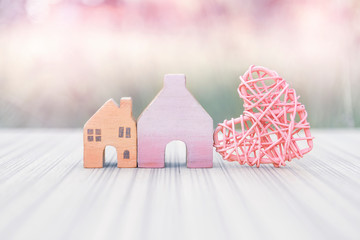 Vintage wooden miniature house with pink wooden heart design over blurred background, vintage filter effect, valentine concept, house and property business