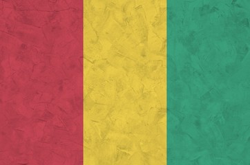 Guinea flag depicted in bright paint colors on old relief plastering wall. Textured banner on rough...