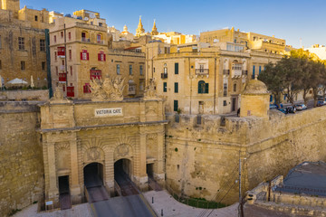 Fototapeta premium Aerial view of Victoria gate in Valletta. The traditional houses, buildings and red maltese balcony on blue sky. Malta country